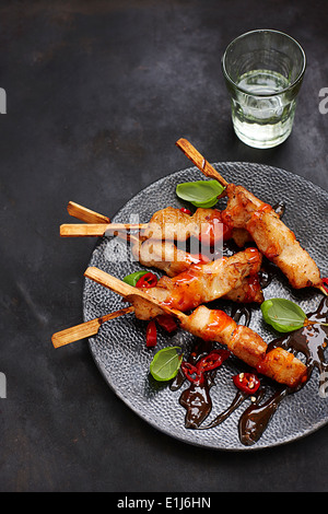 Spiedini di pollo con agrodolci e salsa di peperoncino su piastra Foto Stock