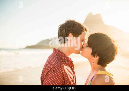 Coppia giovane kissing al tramonto, la spiaggia di Ipanema, Rio, Brasile Foto Stock