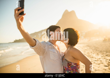 Coppia giovane fotografare sé kissing, la spiaggia di Ipanema, Rio, Brasile Foto Stock