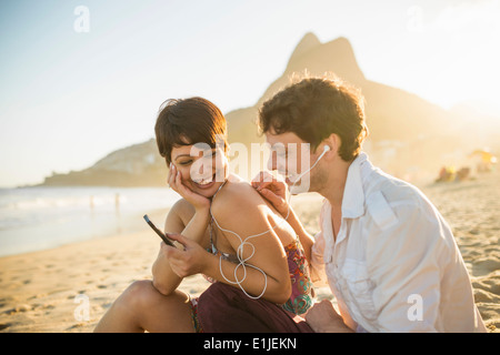 Coppia giovane l'ascolto di musica, la spiaggia di Ipanema, Rio, Brasile Foto Stock