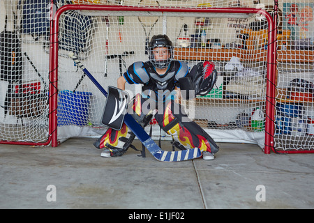 Ragazzo in obiettivo di hockey di indossare abbigliamento protettivo Foto Stock