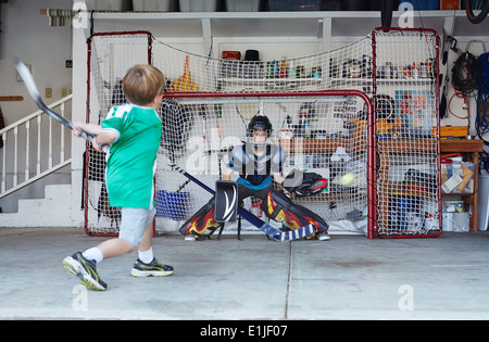 Ragazzi giocare ad hockey in garage Foto Stock