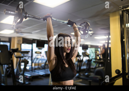 Metà donna adulta utilizzando barbell in palestra Foto Stock