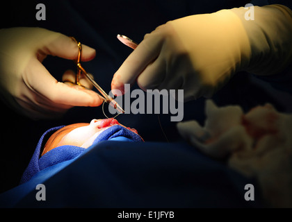 Stati Uniti Air Force Lt. Col. Kerry Latham, un chirurgo plastico con il Walter Reed Army Medical Center, tagli una sutura chirurgica mentre Foto Stock