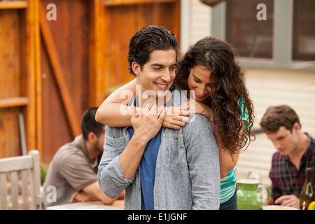 Matura in giardino, con braccio intorno, amici in background Foto Stock