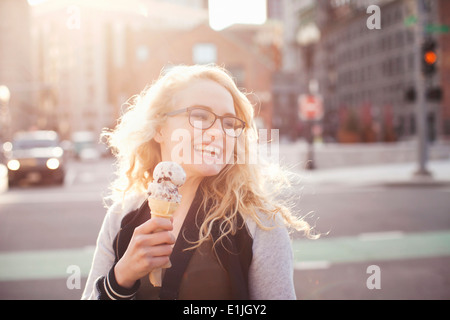 Giovane donna a mangiare il gelato in strada Foto Stock