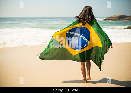 Giovane donna avvolta nella bandiera brasiliana, Arpoador beach, Rio de Janeiro, Brasile Foto Stock