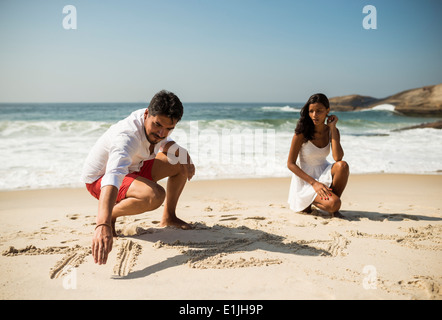 Giovane iscritto nella sabbia sulla spiaggia di Arpoador, Rio de Janeiro, Brasile Foto Stock