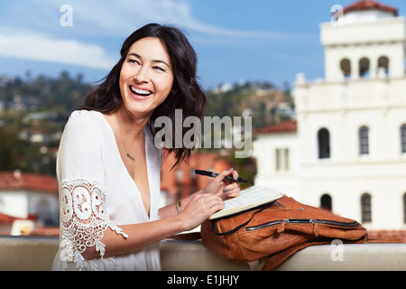 Giovane donna iscritto in notebook all'aperto Foto Stock