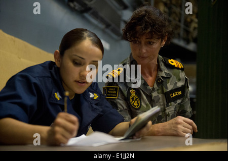 Stati Uniti Navy Hospital Corpsman 1a classe Laura Blanco, sinistra, riempie in Informazioni sul passaporto per Royal Australian Navy Lt. La Cmdr. Vic Foto Stock