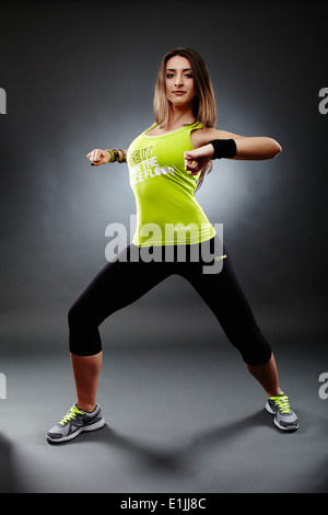 Studio shot di giovani athletic woman dancing e facendo zumba si muove su uno sfondo grigio Foto Stock