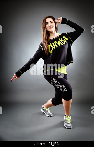 Studio shot di giovani athletic woman dancing e facendo zumba si muove su uno sfondo grigio Foto Stock