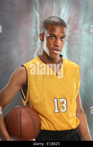 Giovane americano africano giocatore di basket tenendo palla su sfondo di movimento Foto Stock