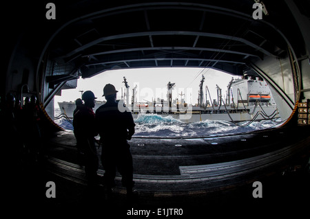 Stati Uniti I marinai a bordo della portaerei USS George Washington (CVN 73) osservare un rifornimento in mare con la flotta rifornire Foto Stock