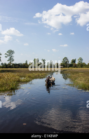 Una barca solitaria vogatore sulla piccola zona umida riserva naturale che è vicino al tempio indù Banteay Srei ad Angkor in Cambogia. Foto Stock