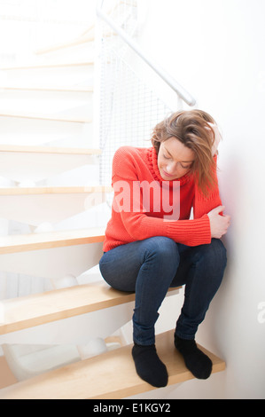 Modello rilasciato donna con la mano tra i capelli su una scala. Foto Stock