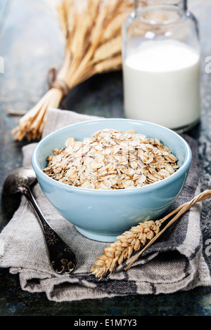 Fiocchi d'avena in una ciotola e latte sulla tavola di legno Foto Stock