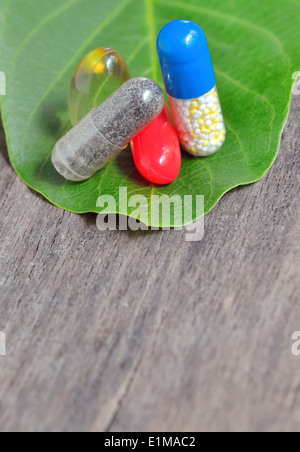 Vitamine, compresse e pillole sulla foglia verde sul vecchio sfondo di legno Foto Stock