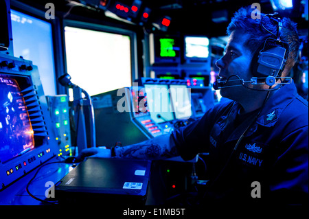 Stati Uniti Navy Fire Controlman 1a classe Aaron Tadlock monitora un radar console nel combattere information center a bordo guidato m Foto Stock