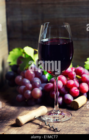 Vino rosso e uva rossa su sfondo di legno. Foto Stock