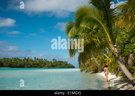 Aitutaki. Isole Cook. Polinesia. Oceano Pacifico del sud. Un turista passeggiate lungo il bordo della spiaggia orlata di palme in un piede Isla Foto Stock