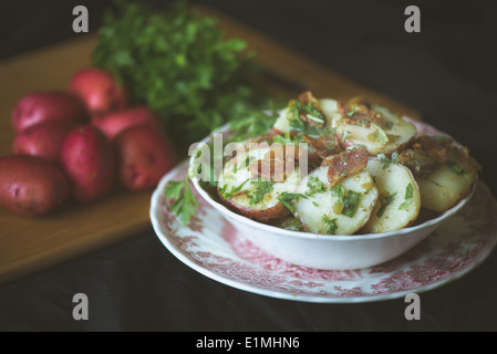 Il tedesco insalata di patate con patate rosse e prezzemolo in background. Foto Stock