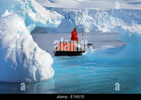L'uomo sightseeing sul piccolo gommone tra gli iceberg in Antartide. Foto Stock