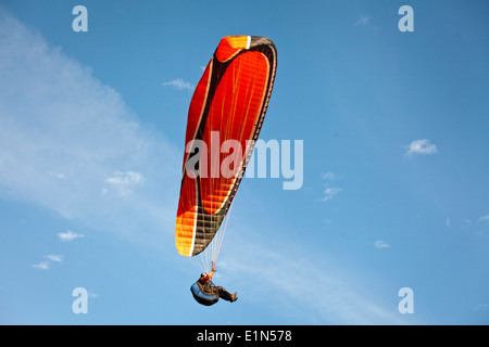 Uomo in parapendio con un red sail contro un cielo blu Foto Stock