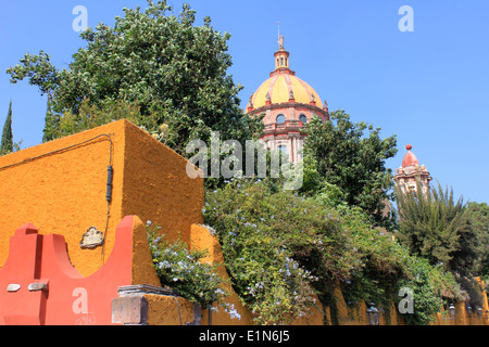 La cupola e il campanile di una chiesa dietro una parete e il giardino di San Miguel De Allende, Guanajuato, Messico Foto Stock