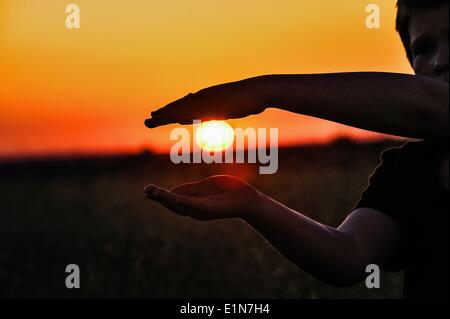 Berlino, Germania. Il 6 giugno, 2014. Un ragazzo telai il sole al tramonto con le sue mani a Berlino, Germania, 06 giugno 2014. Foto: PAOLO ZINKEN/dpa/Alamy Live News Foto Stock