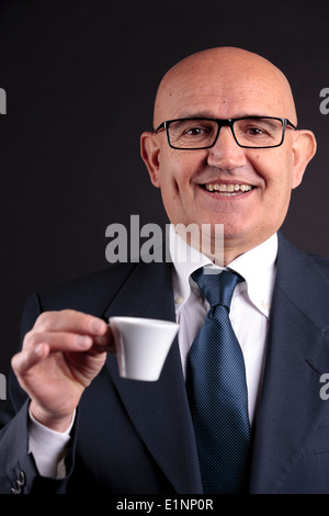 Bald vecchio sorridente imprenditore tenendo una tazza di caffè espresso italiano Foto Stock