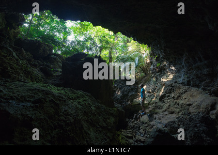 L'uomo esplorare enorme grotta di calcare nel profondo la incontaminata foresta di pioggia di Iriomote isola, a Okinawa, Giappone tropicale Foto Stock