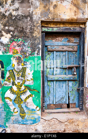 Colori luminosi Indian street life colorita composizione vecchio blu porta e incrinato la pittura religiosa sulla parete grunge India del Sud Foto Stock