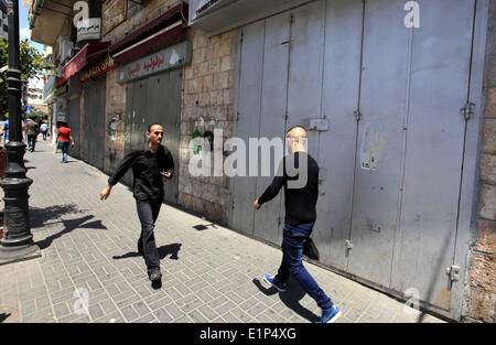 Ramallah, West Bank, Territorio palestinese. 8 Giugno, 2014. Palestinesi a piedi passato negozi chiusi in Cisgiordania città di Ramallah Giugno 8, 2014. I negozi sono state chiuse per la questione palestinese, capitale commerciale di domenica in solidarietà con quasi 300 prigionieri palestinesi in sciopero della fame contro israeliani la detenzione senza processo © Issam Rimawi APA/images/ZUMAPRESS. Foto Stock