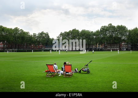 Un paio di guardare una partita di cricket a Vincent Square, Westminster, London. Regno Unito. Questo impianto sportivo appartiene alla scuola di Westminster. Foto Stock