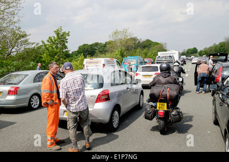Persone in piedi sulla carreggiata della strada al di fuori di veicoli fermi in un ingorgo sull'autostrada M6, a causa di un incidente causando lunghi ritardi. Lancashire England Regno Unito Foto Stock