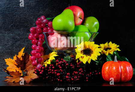 Autunno Autunno still life Vaso con fiori, frutti e bacche contro un drammatico nero ardesia piano cucina dello sfondo. Foto Stock