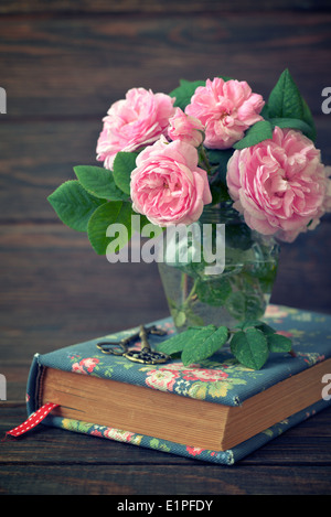 Bouquet di rose di tè in vaso di vetro su sfondo di legno Foto Stock