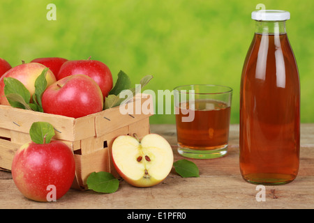 Freschi di succo di mela in una bottiglia e un bicchiere accanto a mele mature Foto Stock