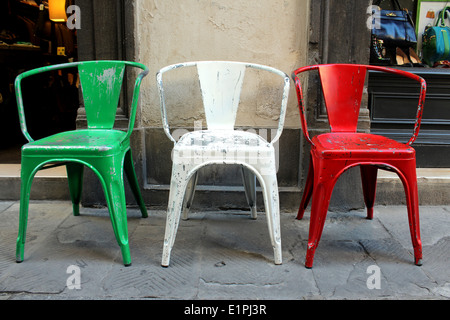 La bandiera italiana e colori rappresentati in tre industriali vintage sedie in metallo sulla strada a Firenze, Italia. Foto Stock