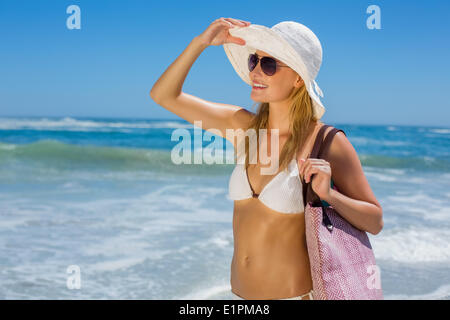 Sorridente bionda in bikini bianco borsa sulla spiaggia Foto Stock
