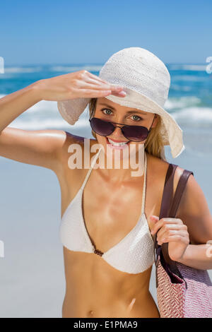 Sorridente bionda in bikini bianco borsa sulla spiaggia Foto Stock