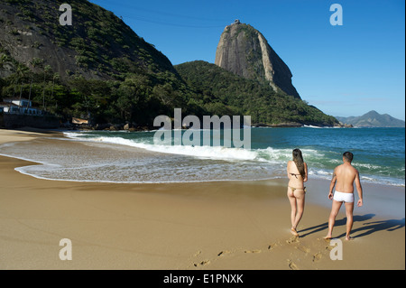 RIO DE JANEIRO, Brasile - 26 settembre 2013: Brasiliano giovane passeggiate a mare a Praia Vermelha Red Beach contro Sugarloaf Mt. Foto Stock