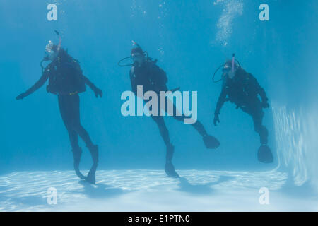 Tre amici sulla formazione di scuba sommerso in piscina Foto Stock