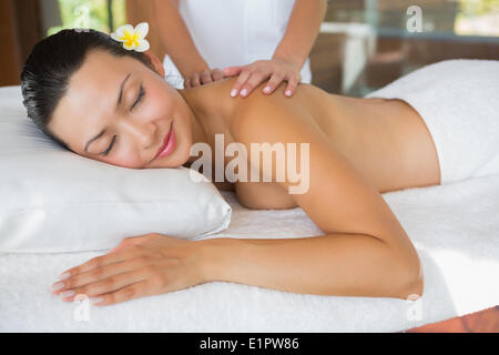 Sorridente brunette ottenendo un massaggio della spalla Foto Stock