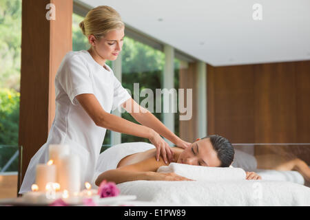 Sorridente brunette ottenendo un massaggio della spalla Foto Stock