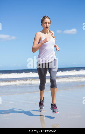 Montare focalizzato bionda jogging sulla spiaggia Foto Stock