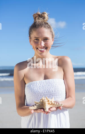 Bella bionda in abito bianco azienda stella di mare sulla spiaggia Foto Stock