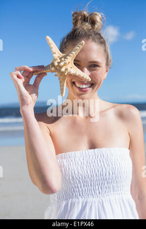 Bella bionda in abito bianco azienda stella di mare sulla spiaggia Foto Stock