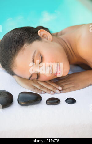 Sorridente brunette giacente su asciugamano avente un massaggio hot stone Foto Stock